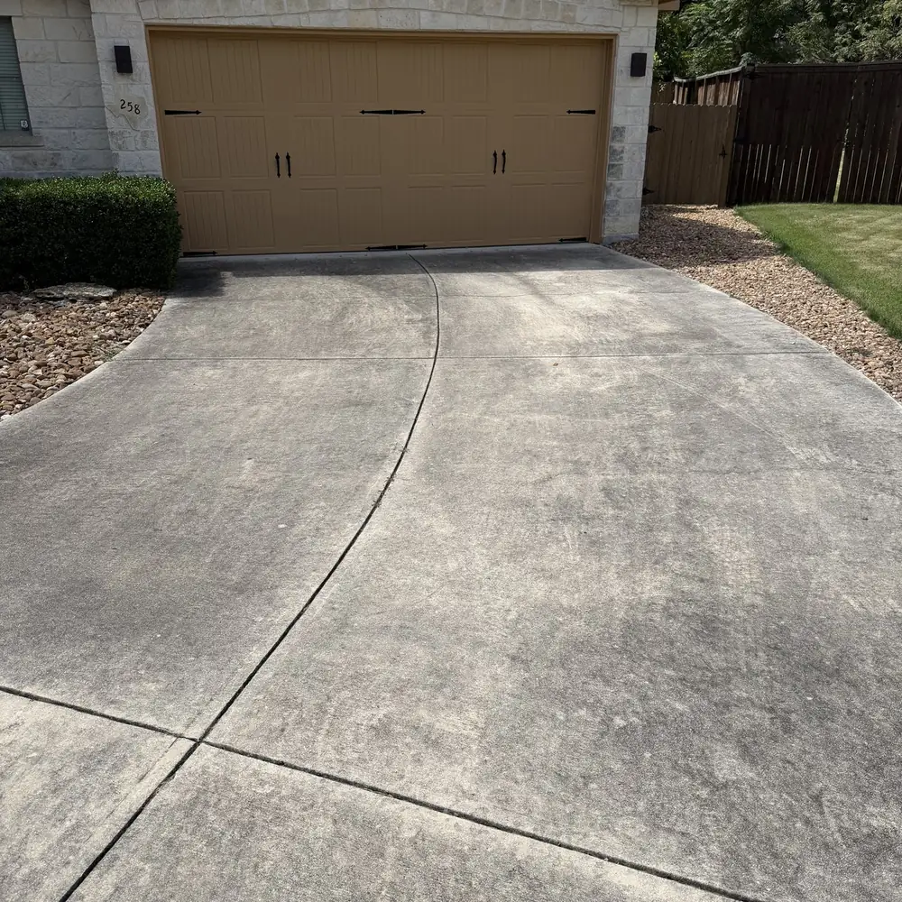 Concrete driveway darkened by dirt, mildew and tire marks before pressure washing in Boerne TX