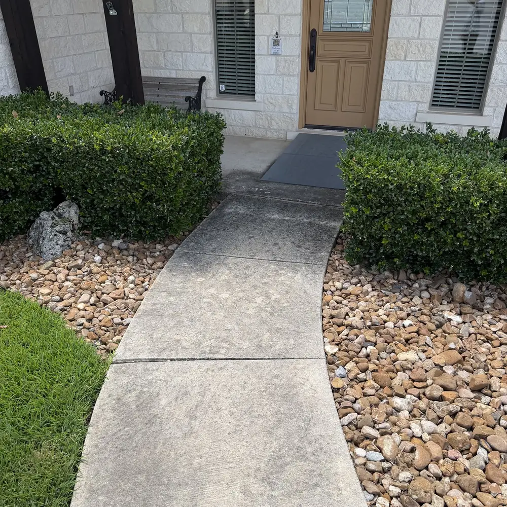 Front walkway with gray organic staining before concrete cleaning at a Hill Country stone home