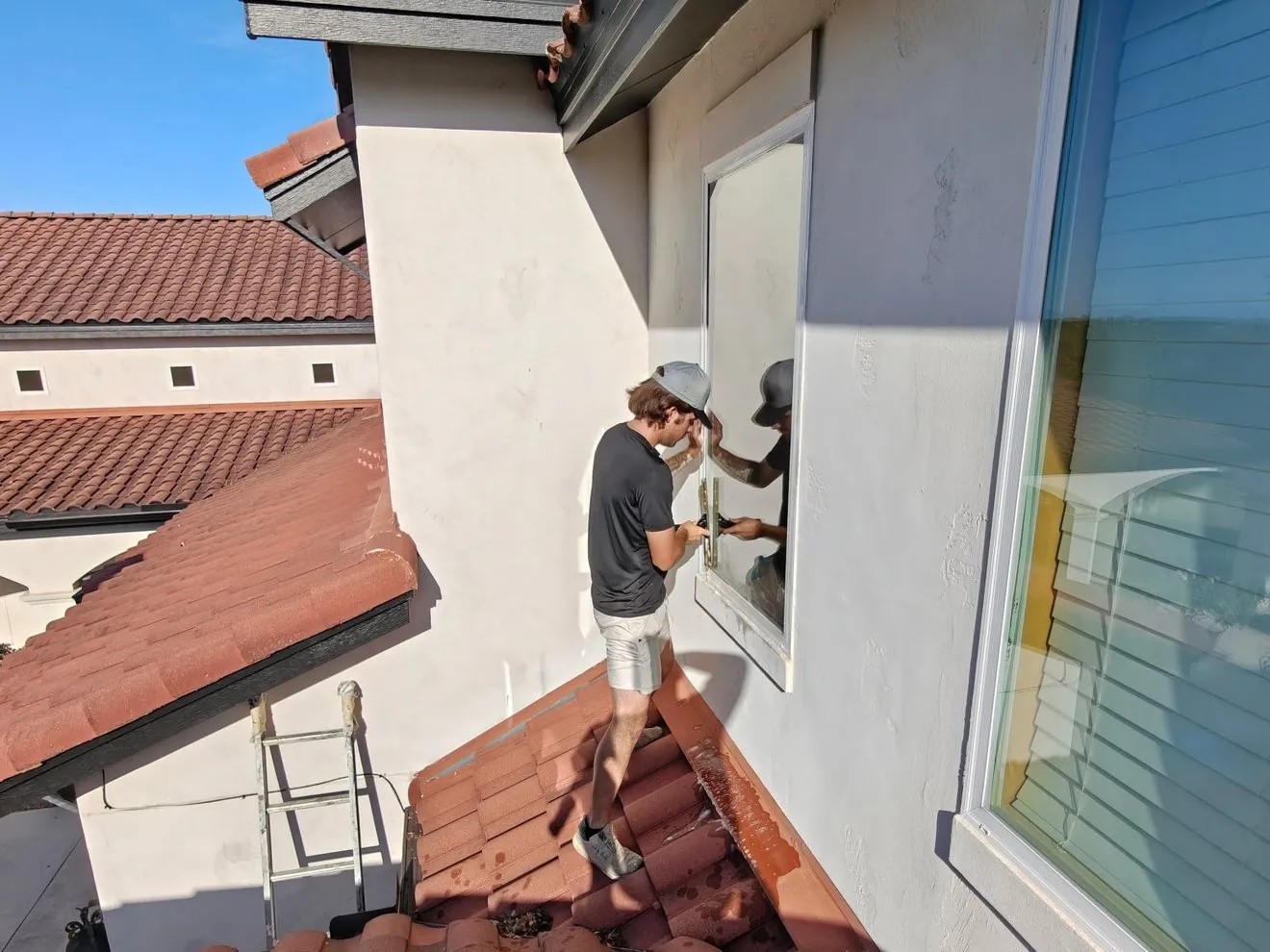 Exterior Wash Pros technician hand-detailing a window above a tile roof in the Texas Hill Country