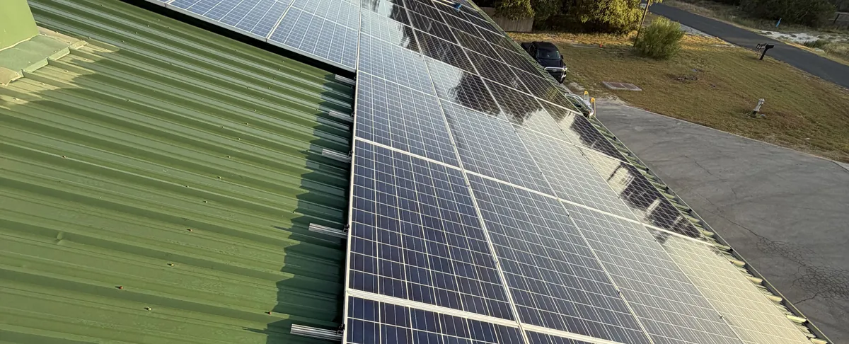 Freshly cleaned rooftop solar panels on a metal roof in the Texas Hill Country